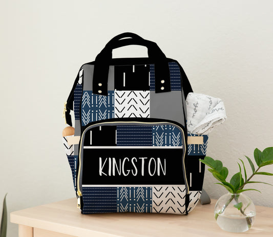 Personalized tribal patchwork diaper bag backpack in blue, black, and white with the name Kingston on front pocket