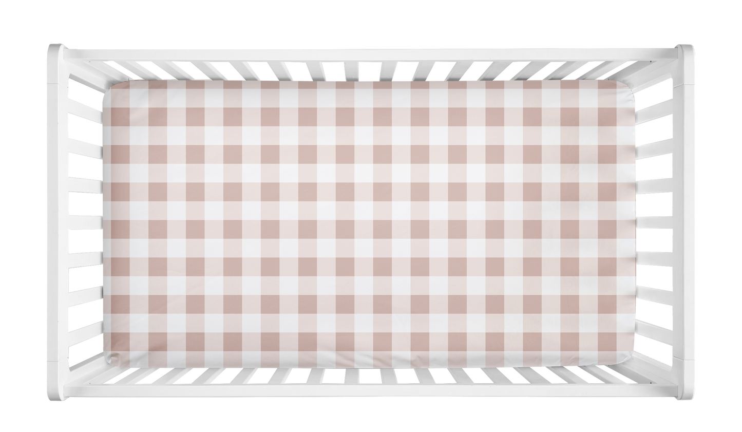 Blush pink and white gingham crib sheet with buffalo check pattern styled in a white crib for a baby girl nursery