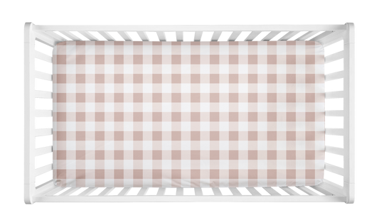 Blush pink and white gingham crib sheet with buffalo check pattern styled in a white crib for a baby girl nursery