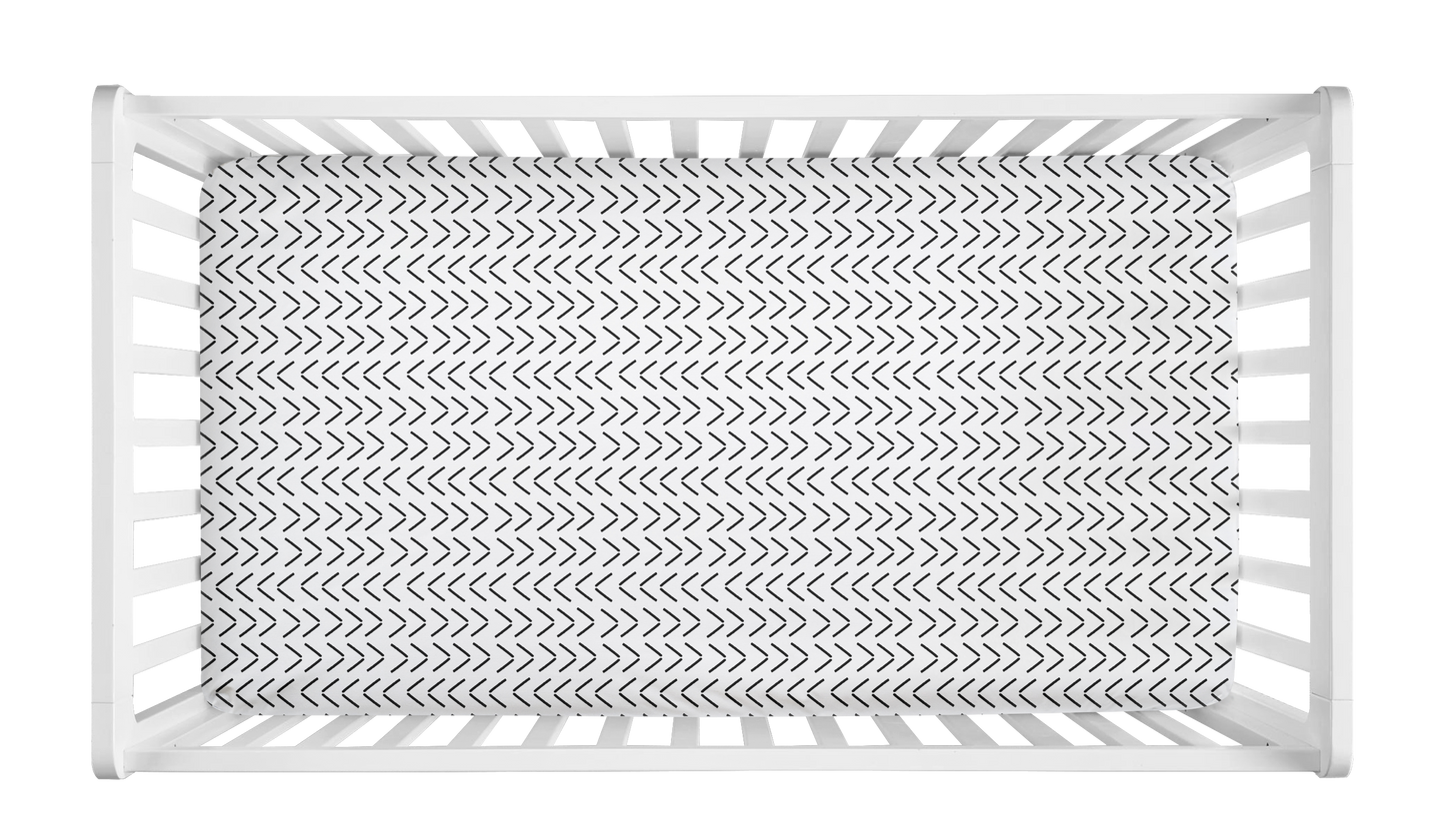 White crib sheet with black mudcloth-style arrow pattern in a modern white crib.
