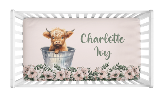 Personalized baby girl crib sheet with Highland cow in a bucket, blush pink background, floral accents.