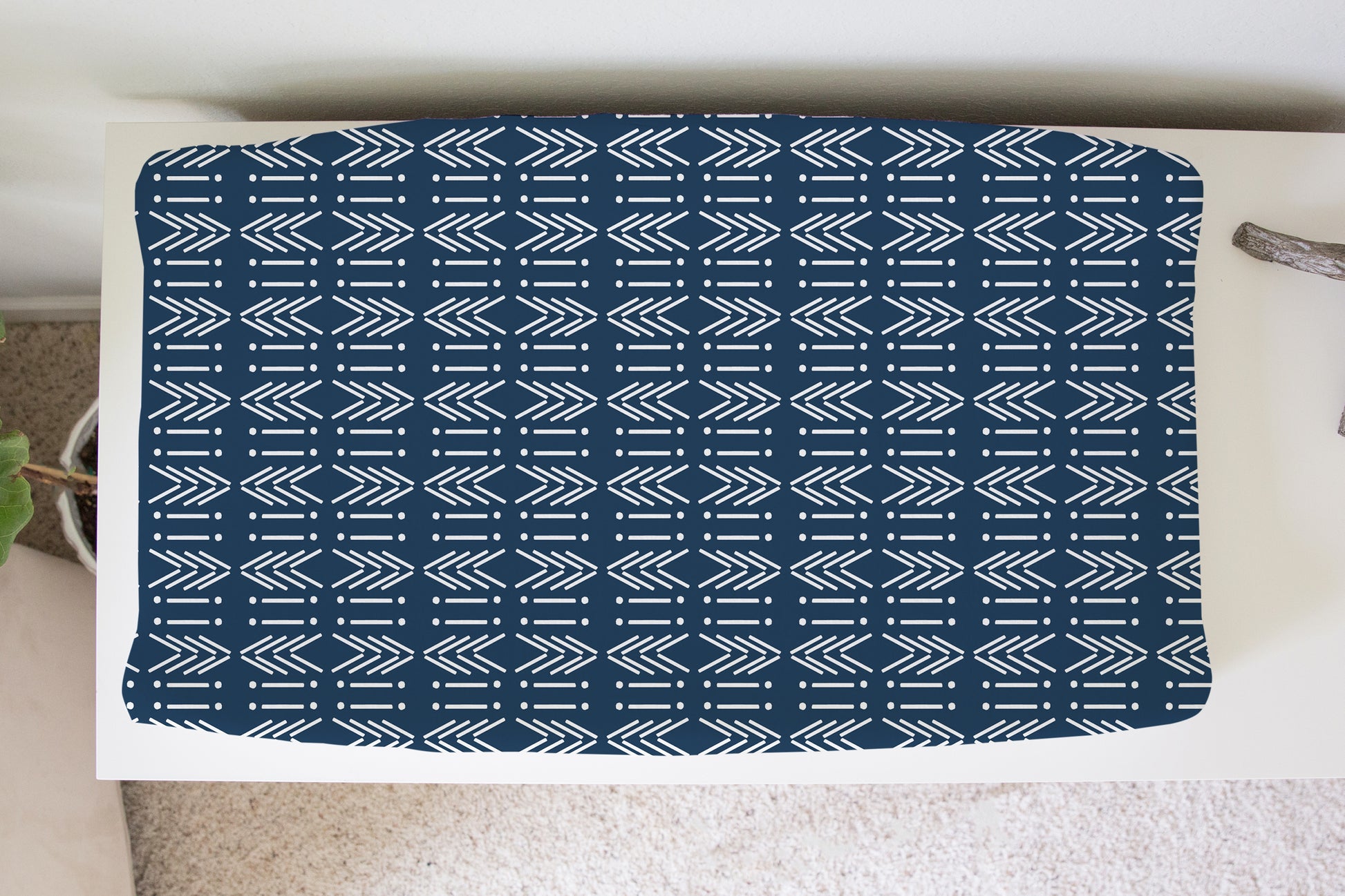 Navy mud cloth arrow print changing pad cover on white dresser in a nursery setting