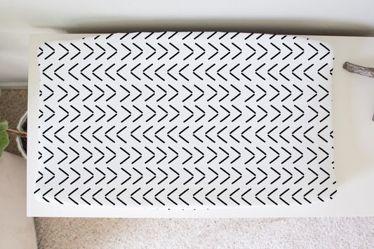 Black and white chevron mud cloth changing pad cover on white dresser in a neutral nursery