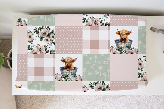 Changing pad cover with patchwork design including blush florals, gingham, sage dandelions, and Highland cows in metal tubs