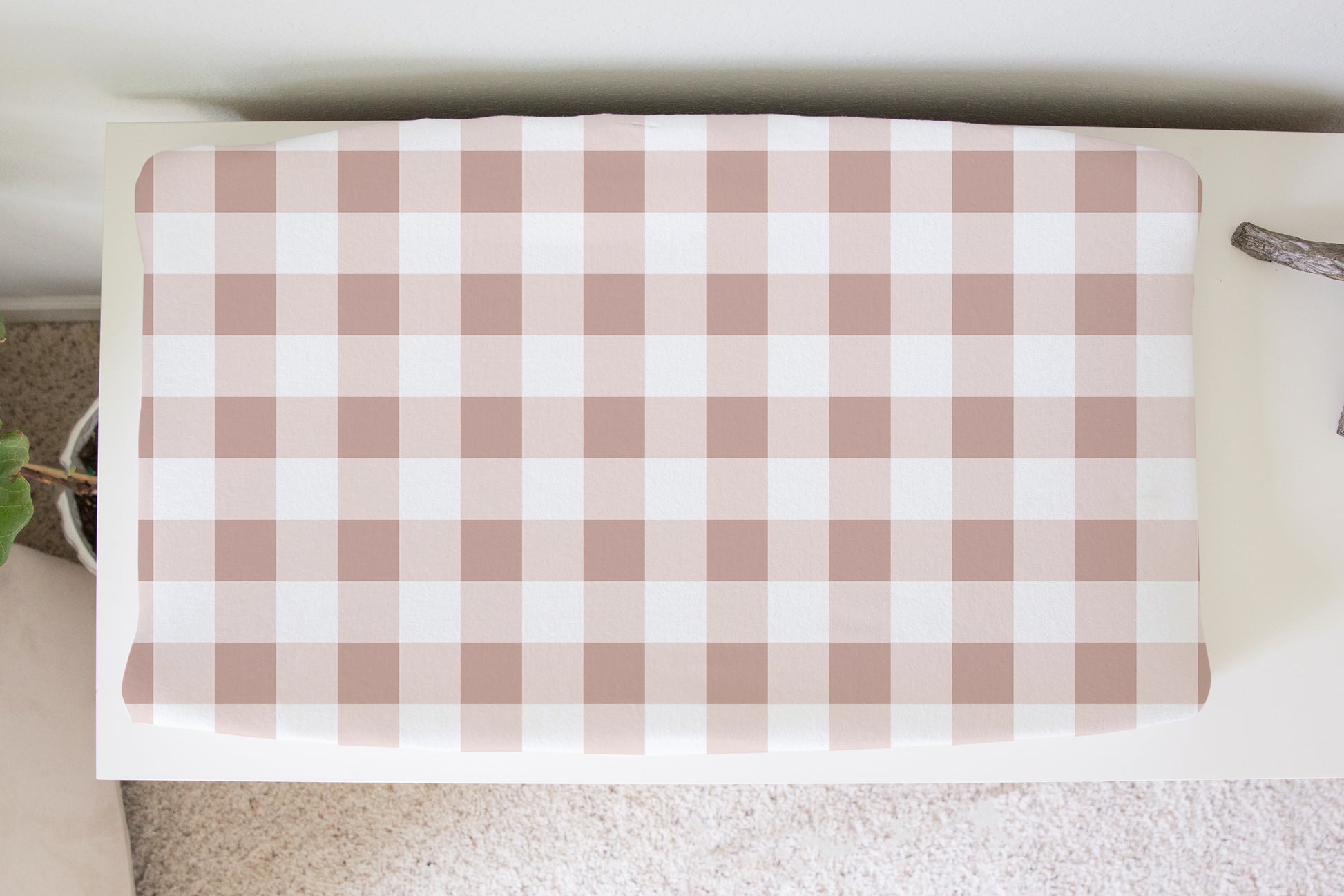 Blush pink gingham changing pad cover with white background on nursery changing table