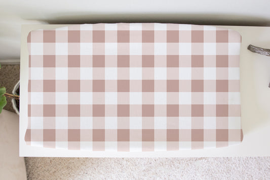 Blush pink gingham changing pad cover with white background on nursery changing table