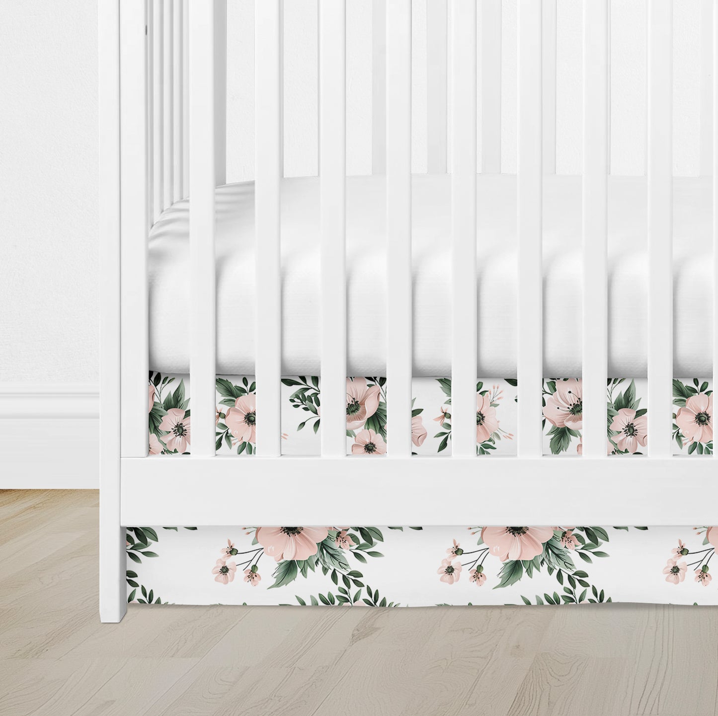 Flat crib skirt in blush pink floral pattern with greenery on white background
