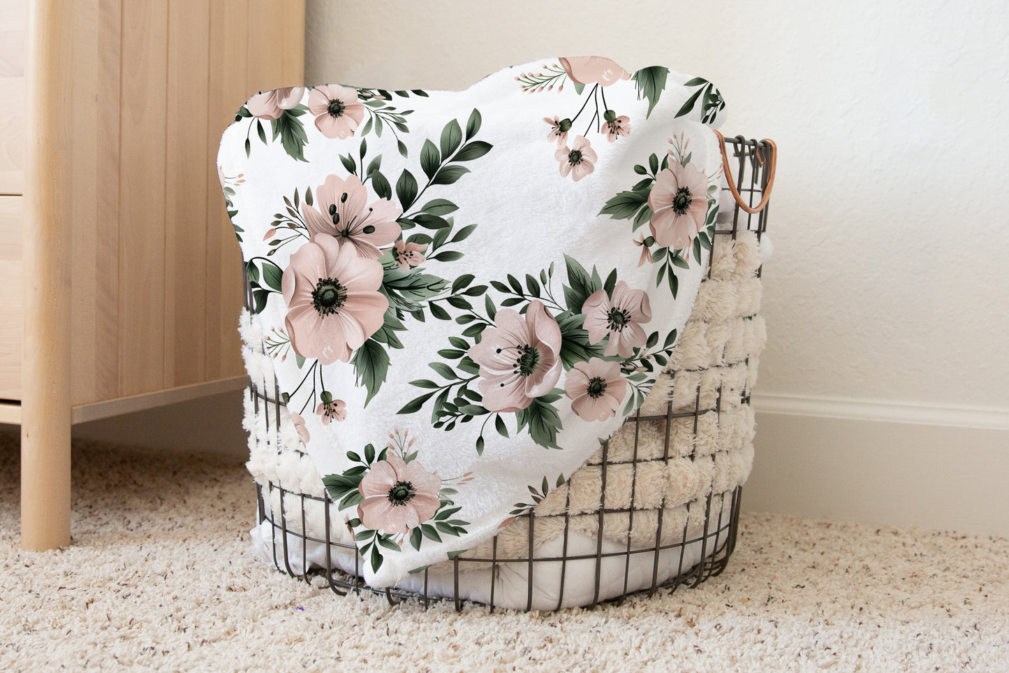 Blush and sage floral baby blanket with sherpa backing, featuring soft pink watercolor flowers and green leaves, styled in a cozy nursery basket
