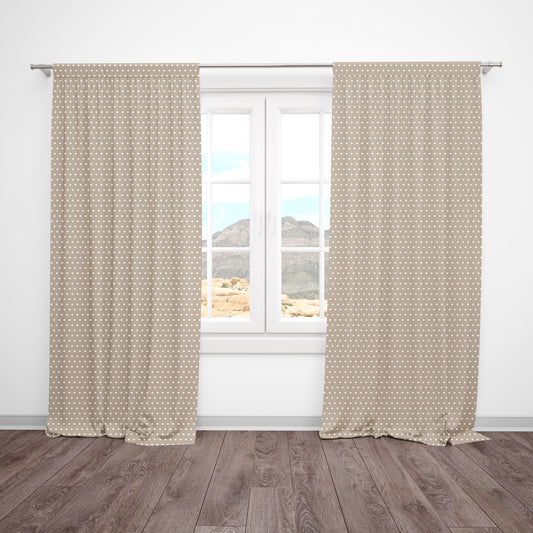 Beige and white polka dot curtains hanging in a neutral baby nursery or kids' room.
