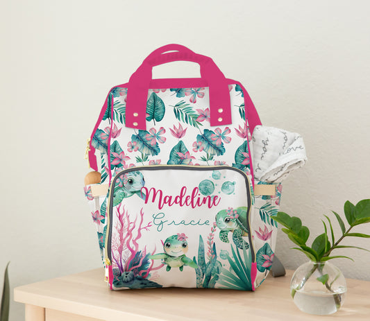 Personalized sea turtle diaper bag backpack with tropical ocean print, pink accents, and custom baby girl name design.