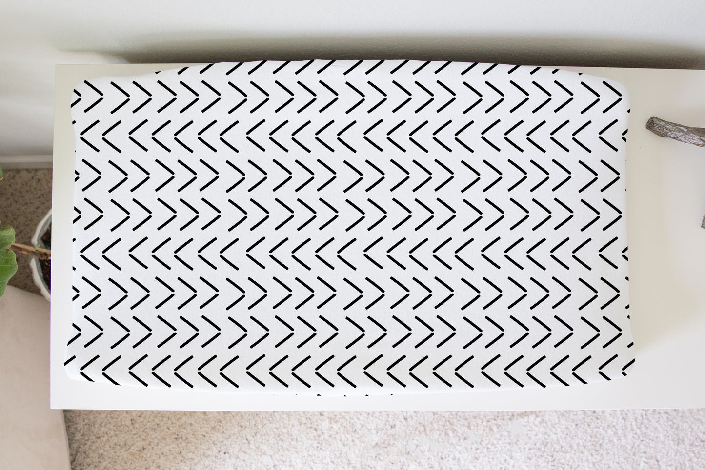 Black and white chevron mud cloth changing pad cover on white dresser in a neutral nursery