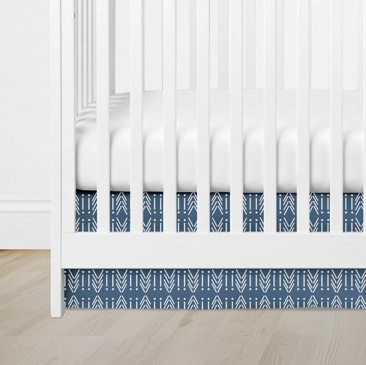 blue crib skirt with white mudcloth arrow pattern under white crib