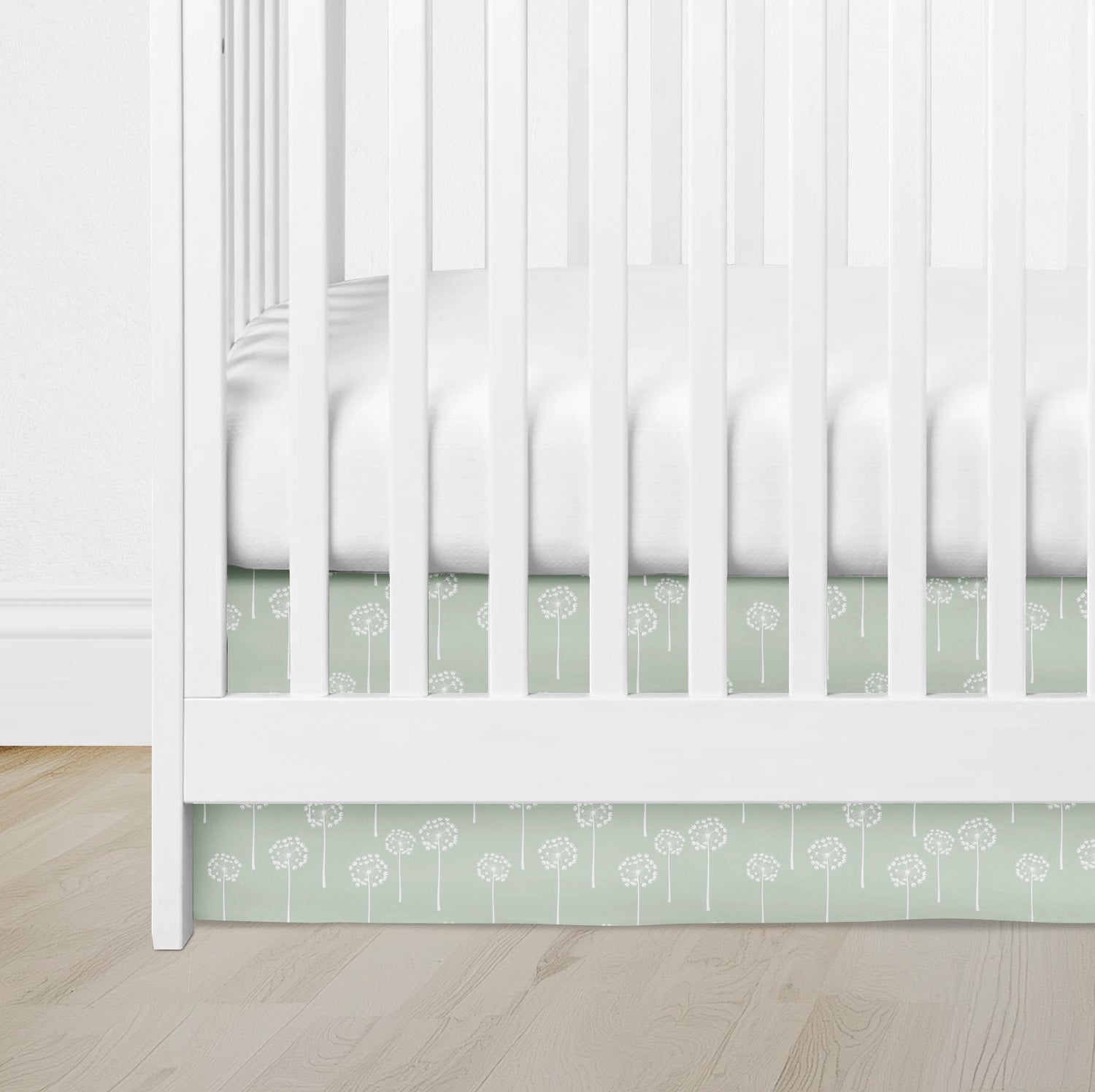 crib skirt with sage green dandelion print, adding a soft, whimsical touch to a white crib.
