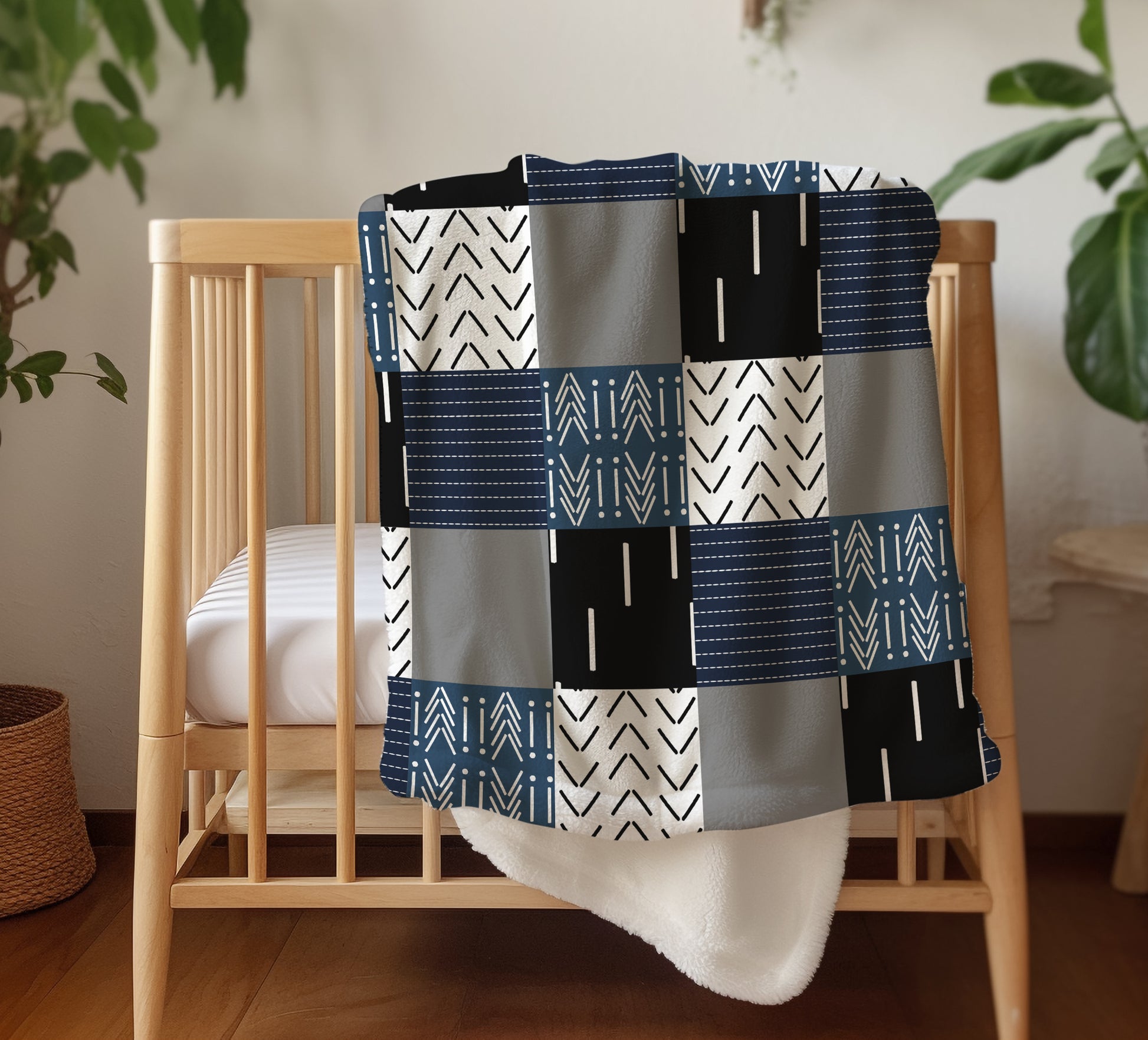 Minky baby blanket hanging on wall with modern tribal patchwork pattern in navy, black, white, and gray.