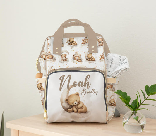 Personalized teddy bear diaper bag with moon and stars design and baby name on front pocket.